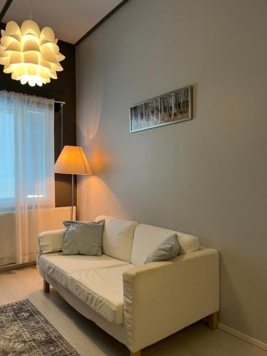a living room with a white couch and a chandelier at Hotelli Keskipiste in Kärsämäki