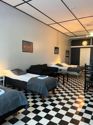 a room with three beds and a checkered floor at Hotelli Keskipiste in Kärsämäki