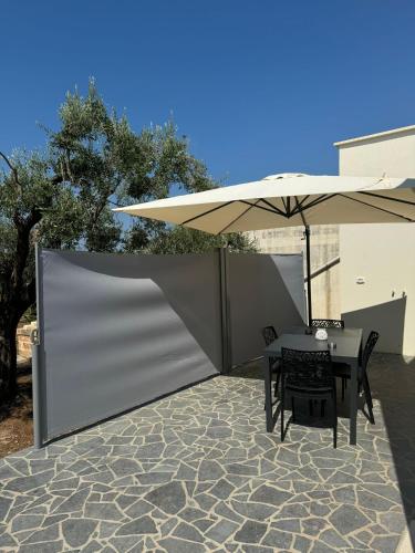 a table and chairs under an umbrella on a patio at Country House in Torre San Giovanni Ugento