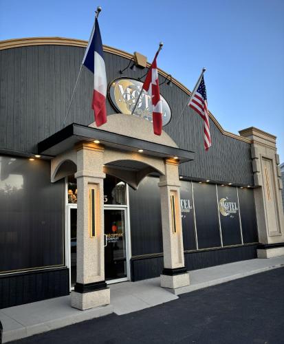a building with three flags in front of it at Motel Cofotel in Saint-Siméon