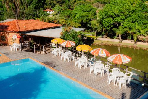 a deck with chairs and umbrellas next to a swimming pool at Pousada Brilho do Sol in Serra Negra