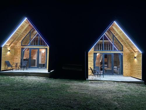 a wooden house with two windows and chairs at night at Eternum Glamping in Žabljak