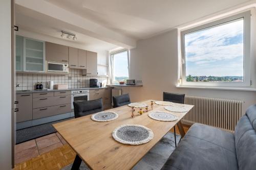 Una cocina y un comedor con una mesa de madera. en TAMLiving Zentrum Luxus Parken Messe WIFI Traumaussicht Sunrise&Sunset, en Graz