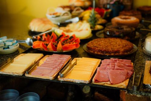 een tafel gevuld met verschillende soorten vlees en kaas bij Pousada Brilho do Sol in Serra Negra