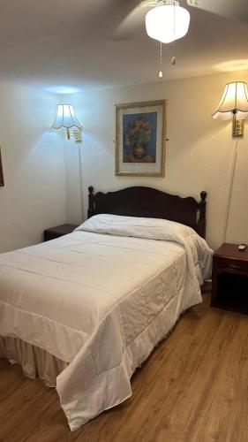 a bedroom with a large white bed with two lights at Gaard motel in Foxborough