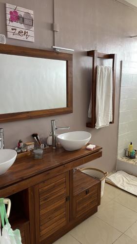 un bagno con due lavandini e un grande specchio di Lucile a Fort-de-France