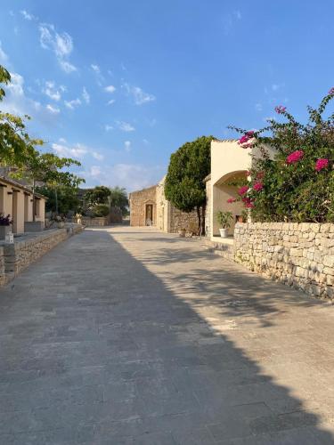 an empty road with a stone wall and a building at Il Carosello dei Baroni in Noto