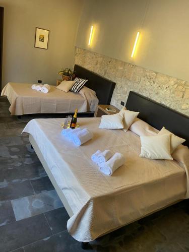 two beds in a hotel room with towels on them at Il Carosello dei Baroni in Noto