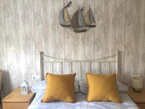 a bedroom with a bed with two yellow pillows at Apartamento El Capricho in Cudillero