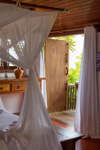 a bedroom with a canopy bed with a wooden porch at Pousada El Gordo in Trancoso
