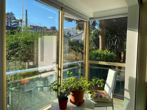 un porche grillagé avec une table et des plantes dans l'établissement Lovely Flat with Covered Balcony in Cannes, à Cannes