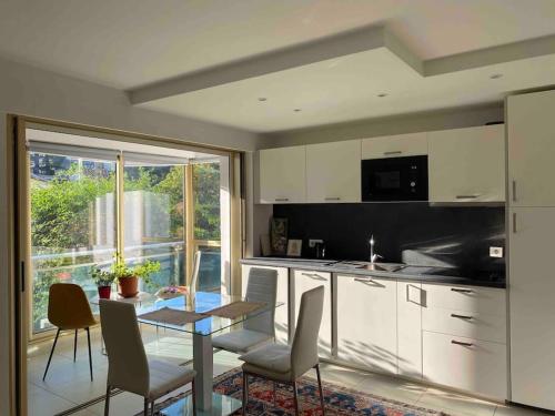 une cuisine avec des armoires blanches et une table et des chaises dans l'établissement Lovely Flat with Covered Balcony in Cannes, à Cannes