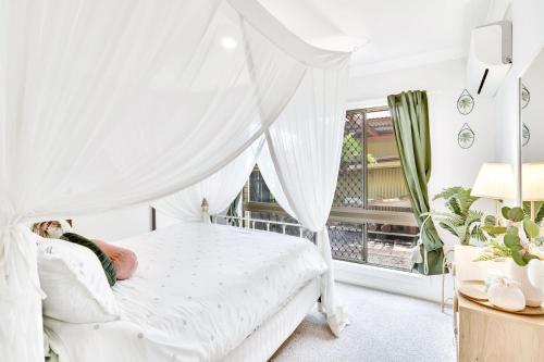 a white bedroom with a bed with a canopy at LakeSide Tinaroo only 2.5km from Yungaburra town in Yungaburra