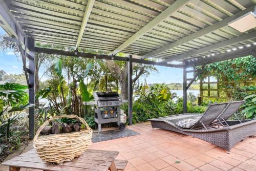 an outdoor patio with a grill and a hammock and a chair at LakeSide Tinaroo only 2.5km from Yungaburra town in Yungaburra