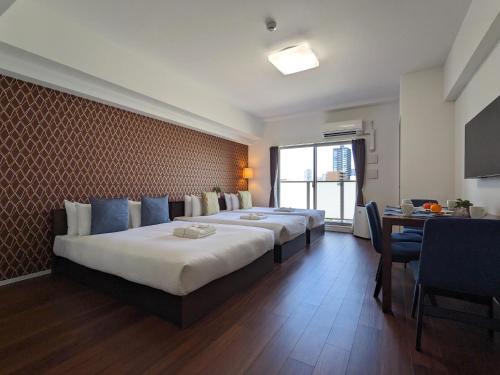 a hotel room with two beds and a table at ESLEAD HOTEL Namba Ebisu West in Osaka