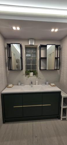 a bathroom with a sink and two mirrors at Casa de la Lac in Baloteşti