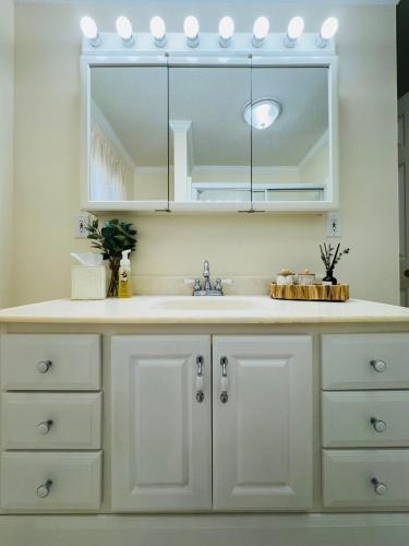a white kitchen with a sink and a mirror at Countryside Carriage House with Pool in Commerce