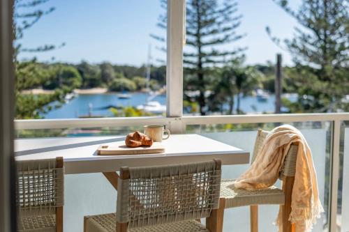 Una mesa y sillas en un balcón con vista al agua. en Penthouse on the Ritz - Oceanstays, en Yamba
