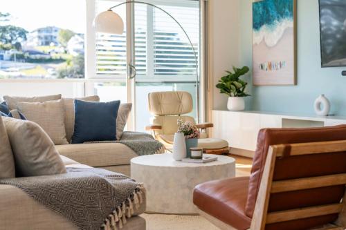 Una sala de estar con un sofá y sillas y una mesa. en Penthouse on the Ritz - Oceanstays, en Yamba