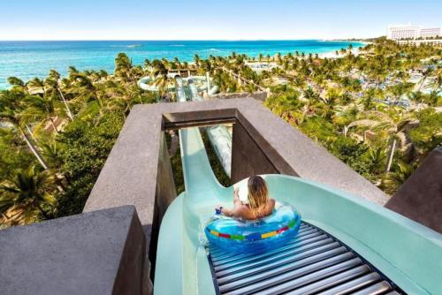 a little girl riding a ride down a water slide at a resort at Beautiful resort 1BD condo with amazing resort amenities pool, kiddie pool, and more in Nassau
