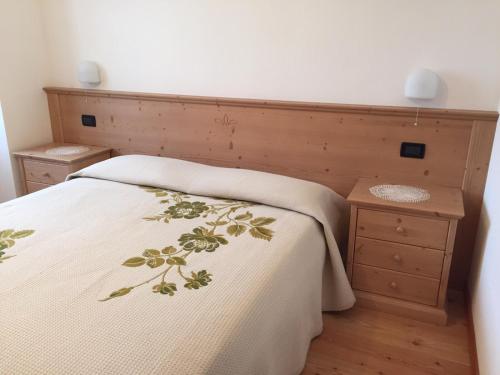 a bedroom with a bed with a wooden headboard at Appartamento Clelia in Pellizzano