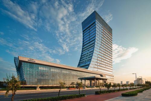 a tall glass building with a street in front of it at Hotel Indigo Yantai Golden Coast by IHG in Yantai