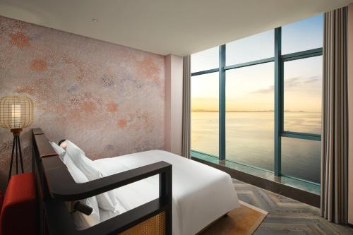 a bedroom with a white bed and a large window at Hotel Indigo Yantai Golden Coast by IHG in Yantai