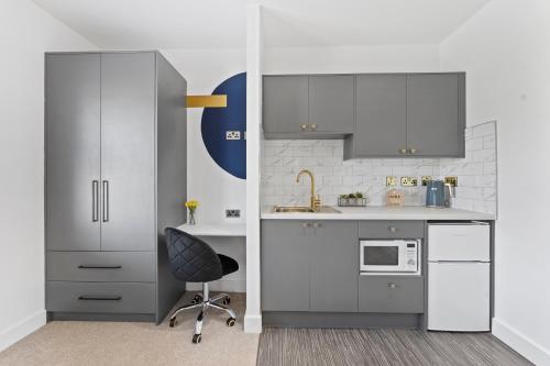 a kitchen with gray and white cabinets and a chair at Westland House En-suite Whole in Peterborough