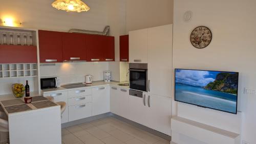a kitchen with white cabinets and a flat screen tv at Apartman Riba in Biograd na Moru