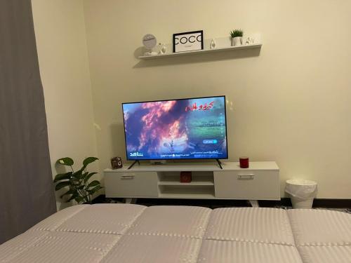 New cairoにあるMivida Coco apartmentのベッドルーム(ベッド1台、ドレッサー内のテレビ付)