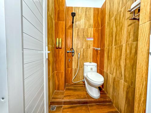 a bathroom with a toilet in a room with wooden walls at Hotel Grand Bandara in Medan