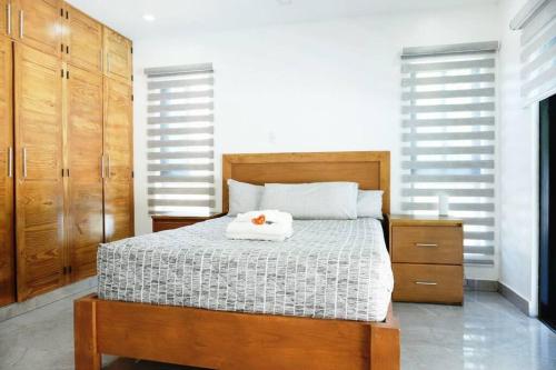 a bedroom with a bed with a white blanket and wooden cabinets at Villa Plasencia! in El Tetero