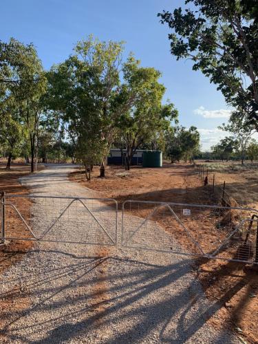 a gate in the middle of a field with trees at Curlew Cottage Katherine in Katherine
