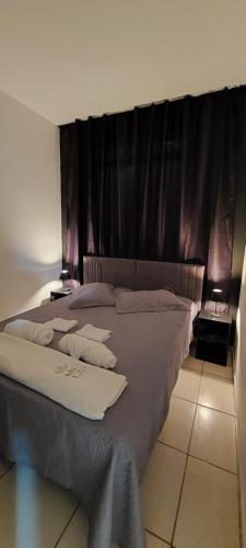 - une chambre avec un grand lit et des rideaux noirs dans l'établissement Apartamento Confortavel 2 quartos ao lado Shopping, à Uberlândia