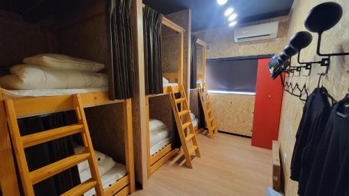 a dorm room with bunk beds and a television at ｹﾞｽﾄﾊｳｽ ﾊﾞｲｸﾔﾉﾆｶｲ in Hagi
