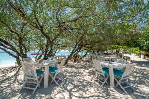 a table and chairs on the beach with the ocean at Wilson's Retreat in Gili Trawangan