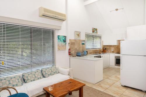 a living room with a white couch and a kitchen at Valley Hideaway - Whole House in Narrawallee