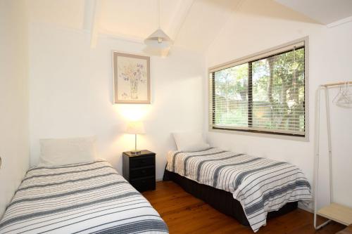 two beds in a room with a window at Valley Hideaway - Whole House in Narrawallee