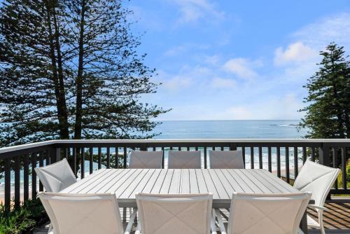 a white table and chairs on a balcony with the ocean at Howth - The Black House by TCC in Newport