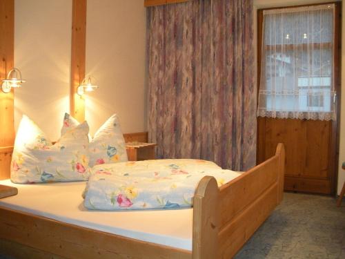 Schlafzimmer mit einem Holzbett mit weißer Bettwäsche und Kissen in der Unterkunft Apartment Christine Öttl in Pfunds