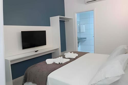 ein weißes Schlafzimmer mit Fernseher und Bett in der Unterkunft Flats confortáveis no Laguna Beach in Porto De Galinhas