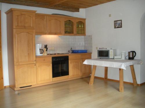 eine Küche mit Holzschränken und einem Tisch mit Mikrowelle in der Unterkunft Apartment Christine Öttl in Pfunds