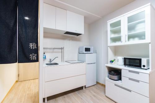 a small kitchen with white cabinets and a microwave at 雅宿nf202最大6名USJまで20分最寄り駅から2分 in Osaka