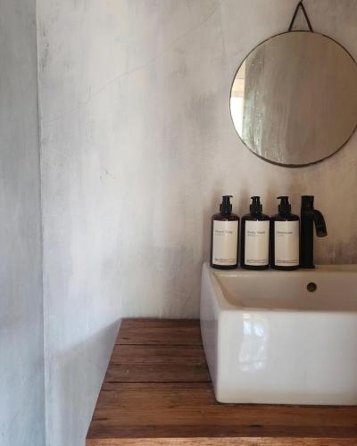 a bathroom with three bottles on a sink at Kayu Cottage in Gili Trawangan