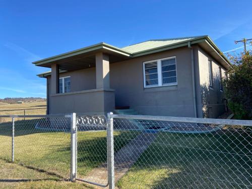 ein Haus mit einem Zaun davor in der Unterkunft Inglewood Cottage in Adaminaby