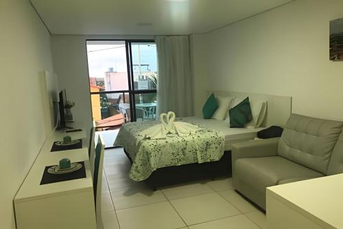 a hotel room with a bed and a couch and a window at Flat Luxo no Laguna Beach in Porto De Galinhas