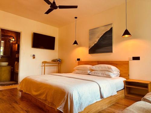 a bedroom with a bed with white sheets and a ceiling fan at Odi Kamadhoo in Kamadhoo