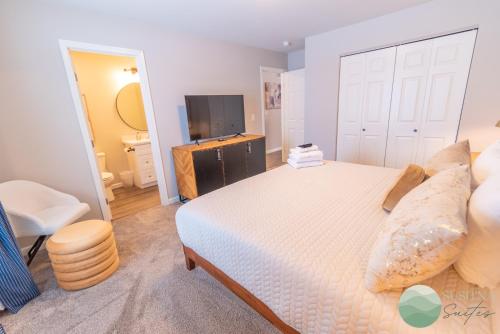 a bedroom with a white bed and a television at Susitna Suites in Wasilla