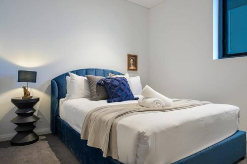 a bed with a blue head board in a room at Brand new 2BD Modern Apt near MQ shopping centre in Sydney