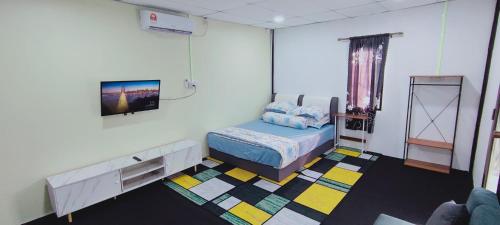 ein Schlafzimmer mit einem Bett und einem Fernseher an der Wand in der Unterkunft Village View Cottage Roomstay in Kemasik